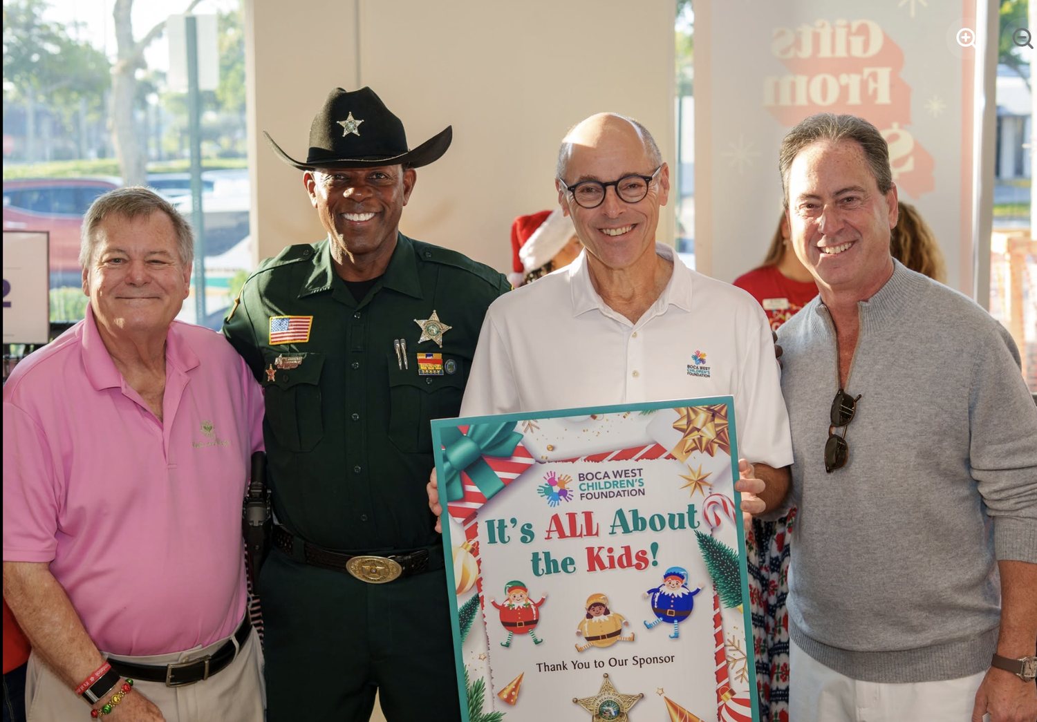 Four men with the It's All About The Kids sponsor sign, including a sheriff's deputy