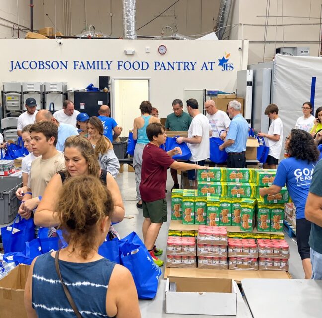 Volunteers packing blue grocery bags at the Jacobson Family Food Pantry