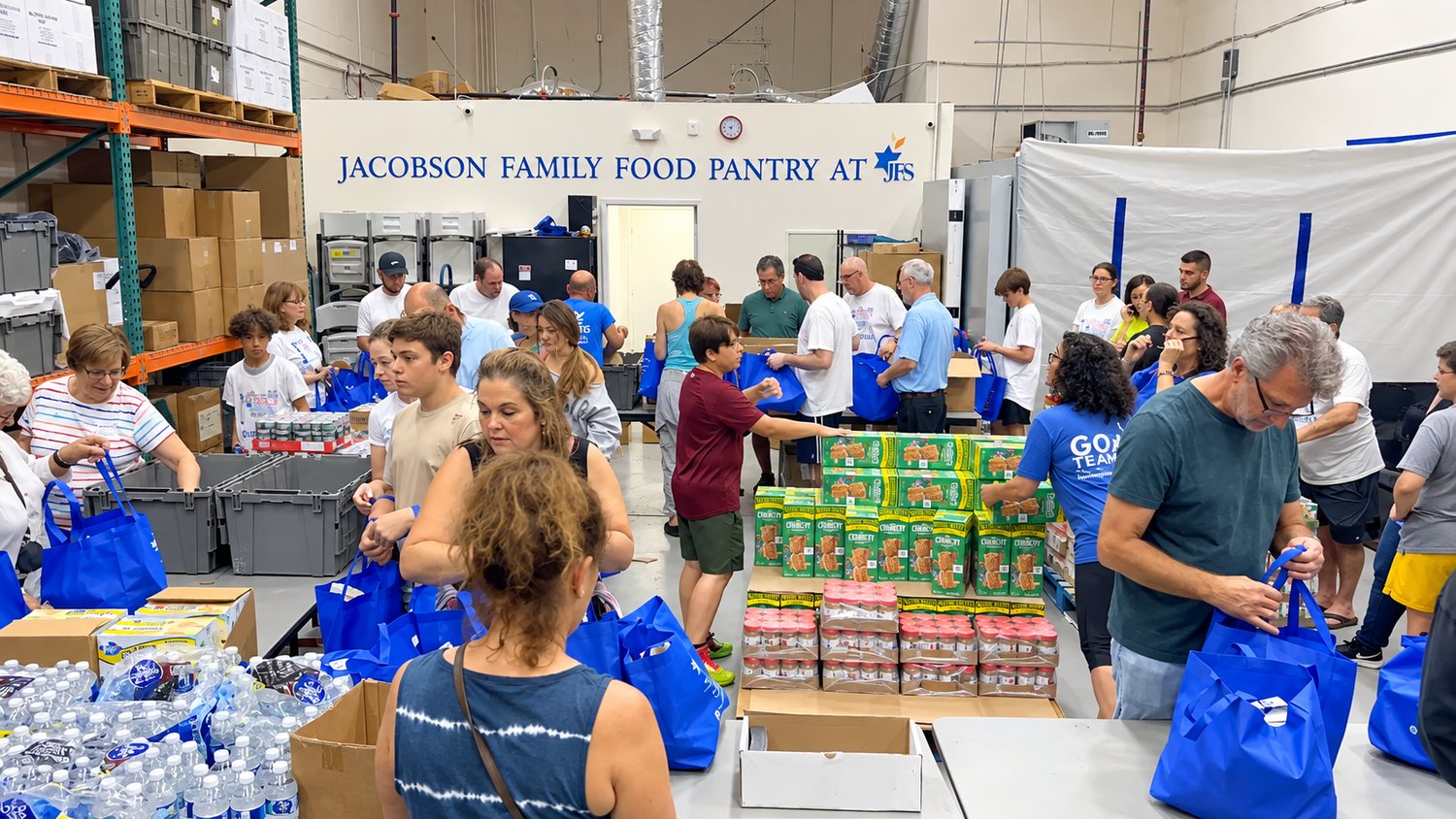 Volunteers packing blue grocery bags at the Jacobson Family Food Pantry