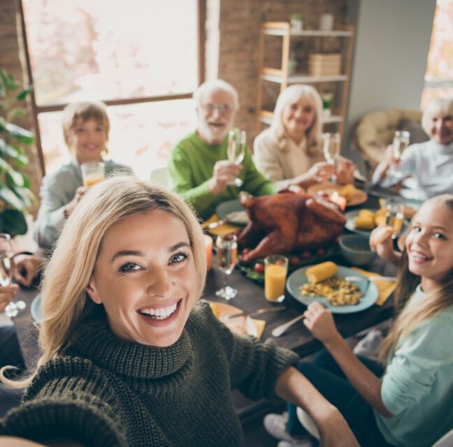 A family gathered around a Thanksgiving table raising glasses